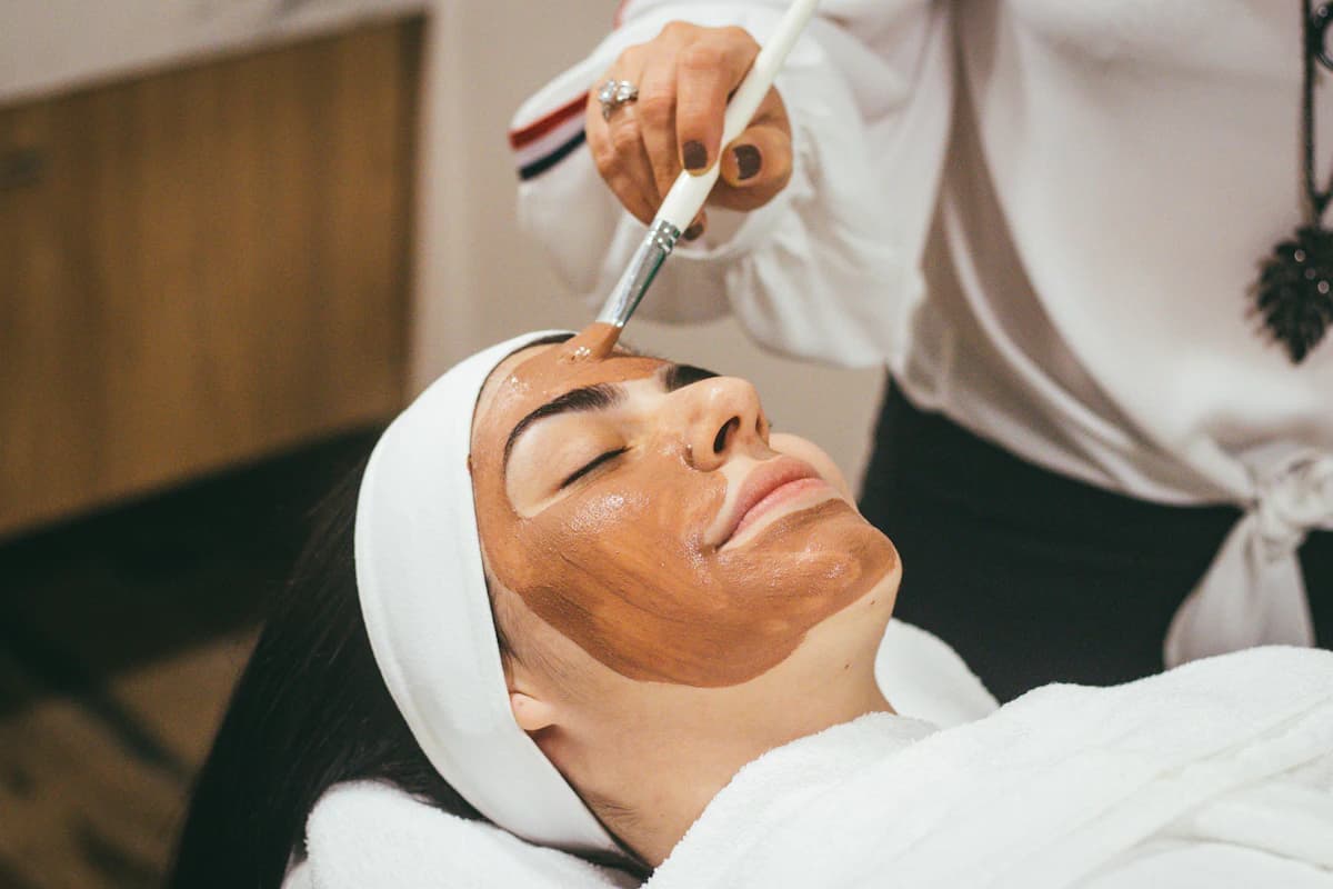 Huidtherapeut behandelt het gezicht van een cliënte met een microneedling-apparaat in een hygiënische praktijkruimte