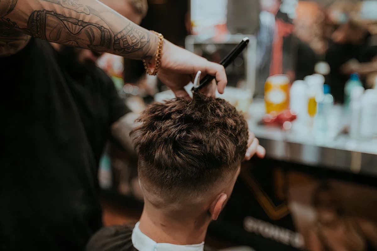 Barbier scheert de baardlijn van een klant met een scheermes in een barbershop
