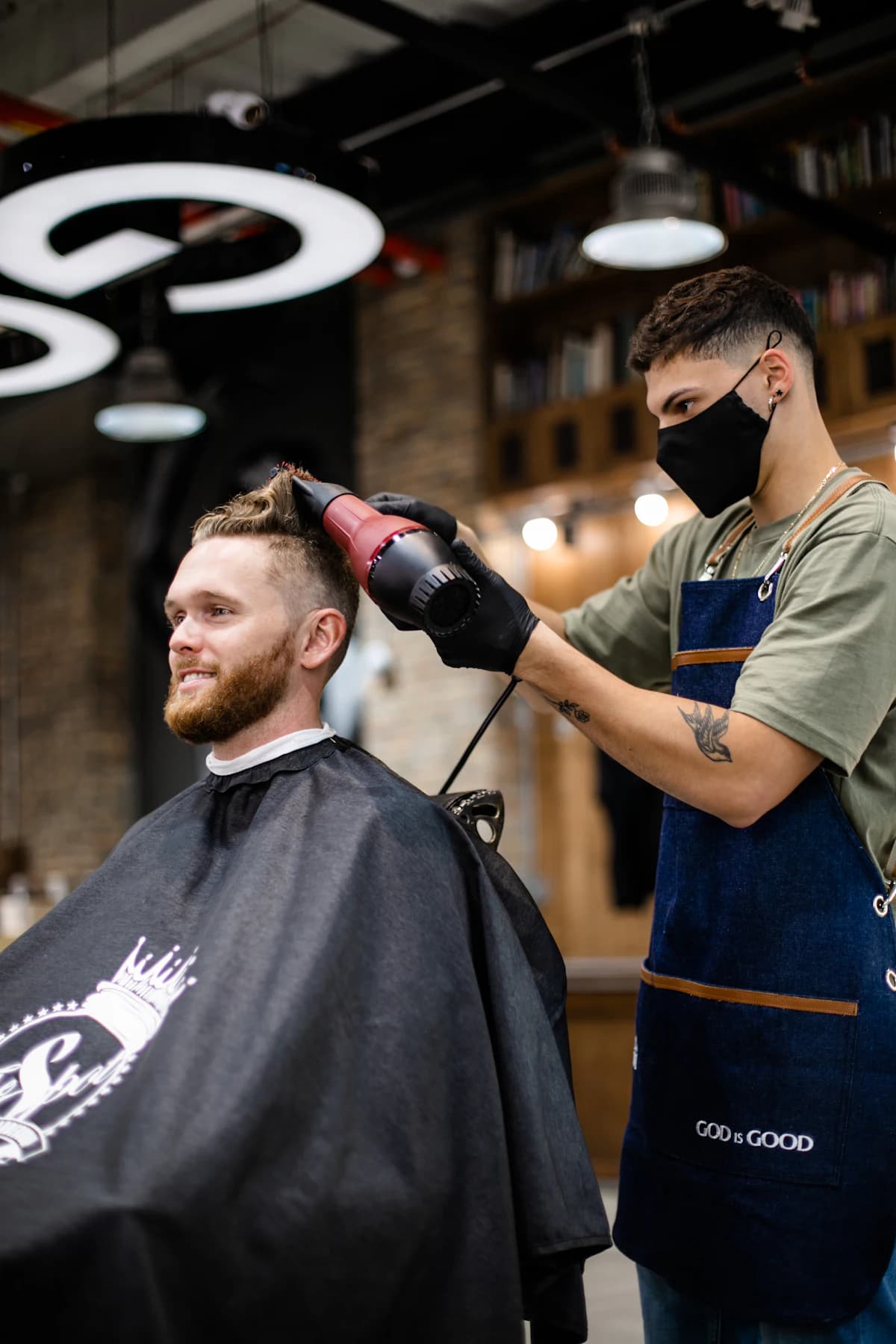 Krullenkapper knipt krul voor krul droog haar bij een klant met krullend haar