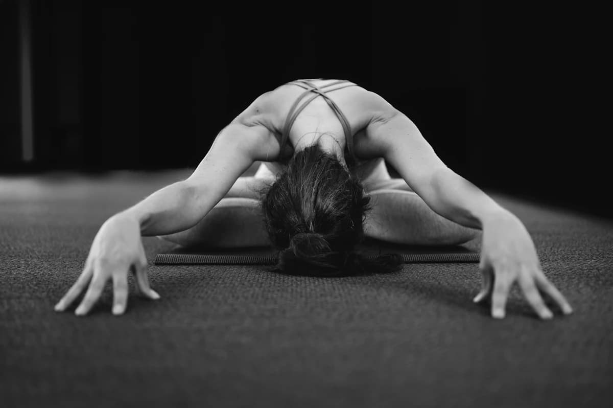 Yogadocent begeleidt een leerling bij de juiste uitlijning tijdens een groepsles in een yogastudio